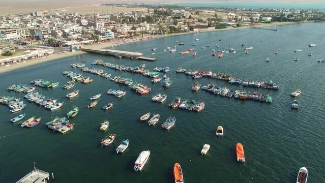 Paracas, Peru: Aerial drone footage of the Paracas town and harbor by the Pacific ocean in Peru, south of Lima. Shot with a forward and tilt up motion. 