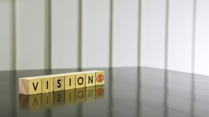 VISION word with eye icon on wooden cube on black gloss wooden table. Background concept for business and presentation. Selected focus.