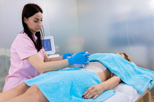 Beautician therapist applying cryolipolysis treatment in beauty salon.