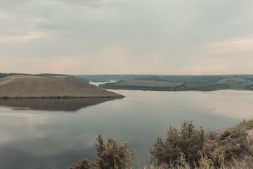 The banks of a large river with smooth calm water. The panoramic landscape. Bakota, Dniester river, Ukraine.