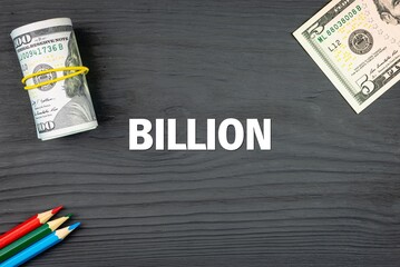 BILLION - word (text) on a dark wooden background, dollars and colored pencils. Business concept (copy space).