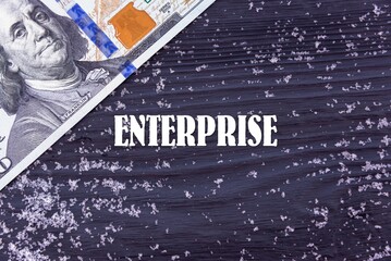 ENTERPRISE - word (text) on a dark wooden background, money, dollars and snow. Business concept (copy space).