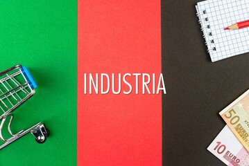 INDUSTRIA - word (text) and euro money on a table of different colors, a trolley, a basket of grocery notepad and a red pencil. Business concept, buying, selling, supermarket, store (copy space).