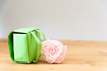 green school backpack made of paper next to a pink flower. copy space. back to school concept