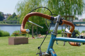 Old racing bike, front end of an old racing bike with handlebar tape made of brown leather on the Neckar meadow in Heidelberg. - obrazy, fototapety, plakaty
