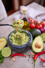 making guacamole - woman holding spoon with mixed minced ingredients