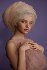 portrait of a beautiful girl in a ball gown with perfect make-up in the studio on a lilac background