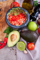 making guacamole - crushed avocado in marble mortar and ingredients
