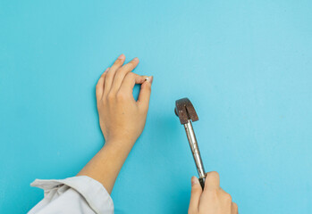 The carpenter hit nail on Aqua blue wall.