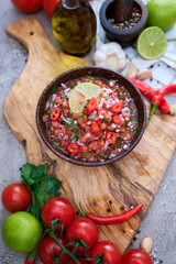 freshly made salsa dip sauce - chopped garlic, tomatoes and onion in wooden bowl