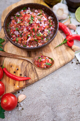freshly made salsa dip sauce - chopped garlic, tomatoes and onion in wooden bowl