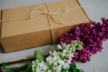 Gift and a branch of lilac flowers. Delivery of goods to the door. The package.