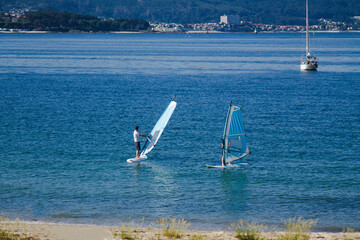 surfers sailing with windsurf board in the water