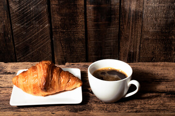 Breakfast food coffee and croissant in plate on wood table.