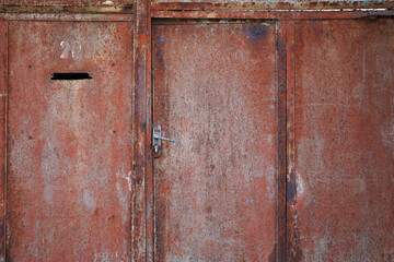 Flaking paint and rust on gates of abandoned building.