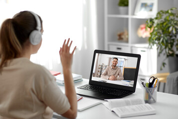 school, education and distance learning concept - happy smiling female student with teacher on laptop computer screen having video call or online class at home