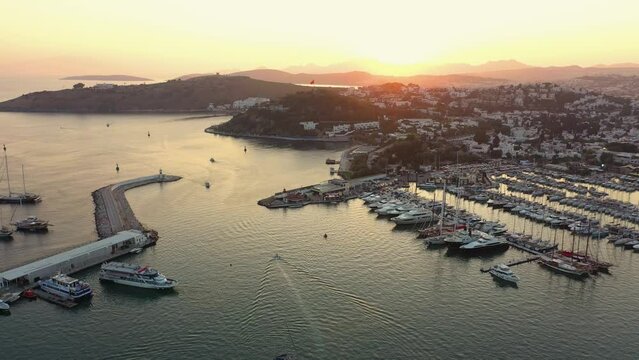 Picturesque sunset scene of Bodrum town and boats at harbor. Beautiful aerial view of resort town on Mediterranean coast.