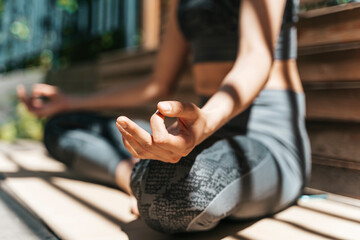 A woman meditates in the lotus position and relaxes in nature in the park in summer sunny weather. Yoga, mental health, relaxation, health concept.