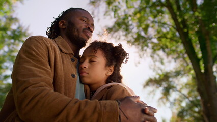 Portrait father hug daughter closing eyes in golden sunlight. Dad love support.