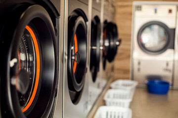 Row of industrial laundry machines in laundromat.