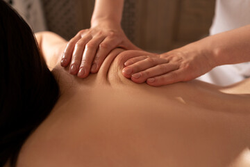 Fototapeta na wymiar Deep tissue massage close-up. Woman having massage of body in the spa salon. Charming lighting. beauty treatment