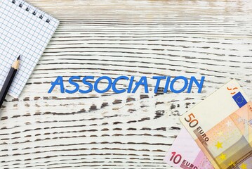 ASSOCIATION - word (text) and euro money on a white wooden table, notebook, notepad. Business concept: buying, selling, commerce (copy space).
