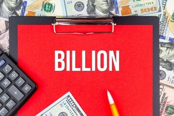 BILLION - word on the background of money (dollars), a notepad and a pen with a calculator. Business concept (copy space).