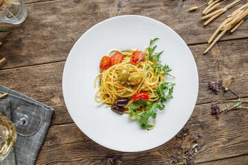 Portion of italian spaghetti pasta with olives and herbs