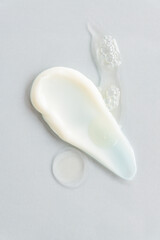 yellow beauty face oil and face cream smear on gray background. Skin care cosmetic advertisement with copy space.