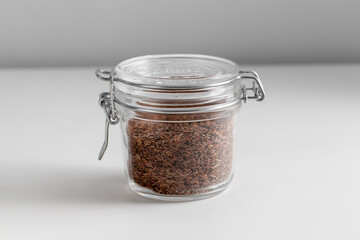 food storage, healthy eating and diet concept - close up of jar with flax seeds on white background