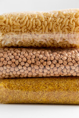 food storage, healthy eating and diet concept - close up of bags with dried peas, pasta and bulgur on white background