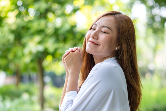 Portrait image of a young woman closed her eyes and enjoying in the park