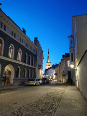 Fototapeta na wymiar One of the cobbled streets of Old Tallinn with a spire against the blue sky. Spring evening. Wanalynn area.