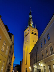 Old houses and the Baptist Church of St. Olaf on one of the streets of Old Tallinn against the dark blue sky. Spring evening.