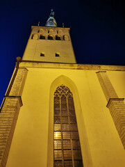 The large white St. Olaf Baptist Church on one of the streets of Old Tallinn against a dark blue...