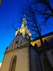 The large white St. Olaf Baptist Church on one of the streets of Old Tallinn against a dark blue...