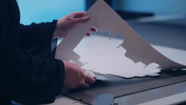 An employee in a factory assembles packaging from cut-out paper.