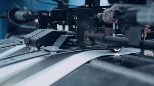 A cutting machine cuts a large pile of paper in a printing house.