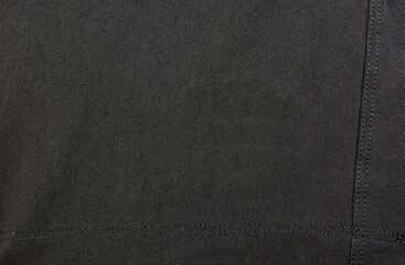 Black textile with a machine stitch used in the garment industry.