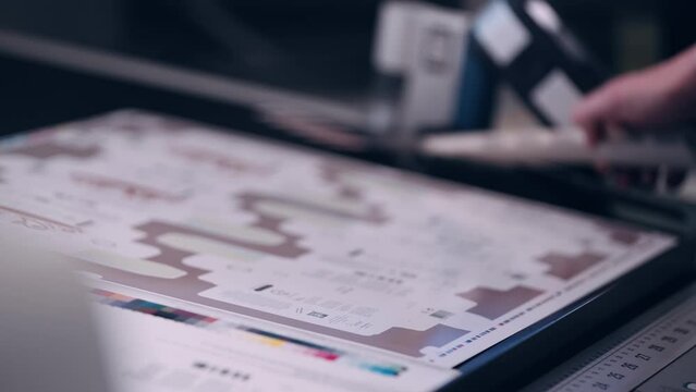 A worker in the printing house checks the quality of the printed packaging.