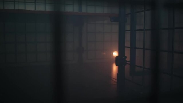 A dark scary room with bars and cages with dim lighting