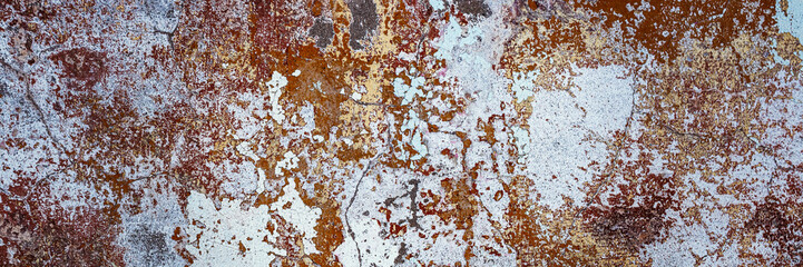 Peeling paint on the wall. Panorama of a concrete wall with old cracked flaking paint. Weathered rough painted surface with patterns of cracks and peeling. Wide panoramic grunge texture for background