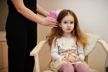 Mom with dauhter making everyday routine together. Mother is brushing and drying child hair after shower.