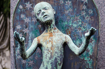 La statua di bronzo ossidato di un bambino circondato dalle stelle sopra una tomba del cimitero...