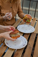 Girlfriends in the restaurant and juicy burgers in their hands. Communication and lunch burgers in a good company of like-minded people. Girls are ready to eat delicious burgers. Lunch with a friend