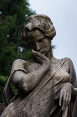 Fototapeta na wymiar La statua di una donna sofferente sopra una tomba del cimitero monumentale di Milano