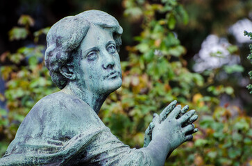 Il volto di bronzo ossidato di una donna sofferente sopra una tomba del cimitero monumentale di Milano