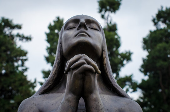 La statua di una donna disperata che prega su una tomba del cimitero monumentale di Milano