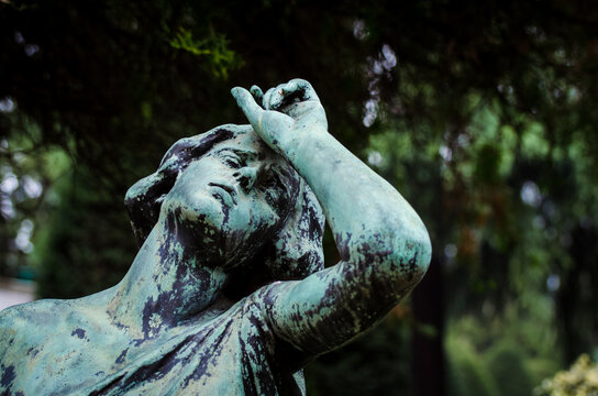 Il volto di bronzo ossidato di una donna sofferente sopra una tomba del cimitero monumentale di Milano