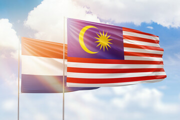 Sunny blue sky and flags of malaysia and netherlands